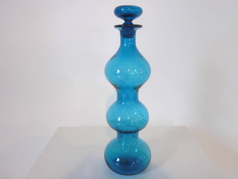 A blue stoppered vase with three bulbous forms, one of the best and most iconic 1950s designs from Blenko and glass blower Wayne Husted, in the rare smaller scale size, retains the paper label to the bottom, manufactured by the Blenko Glass company,