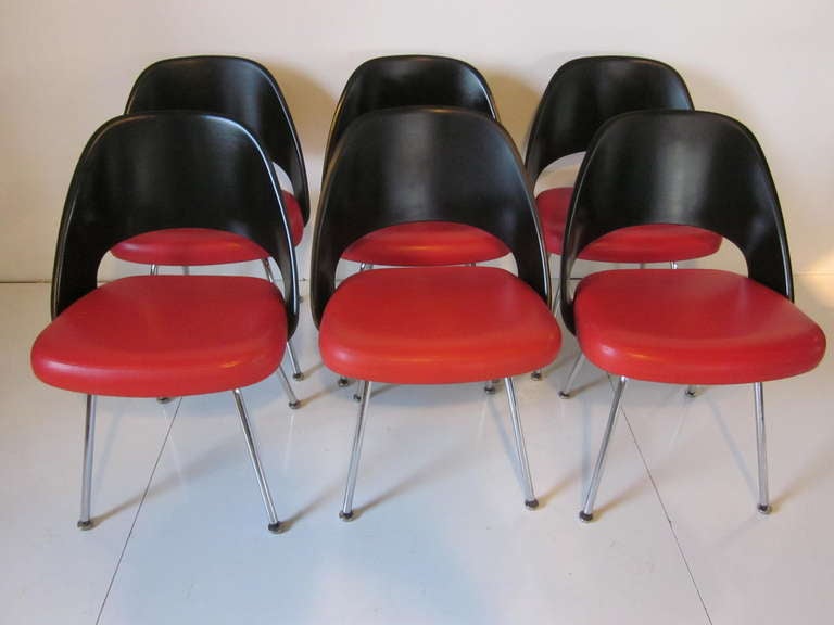 A set of six Sarrinen dining chairs with satin black fiberglass backs and red upholstered Naugahyde seat bottoms sitting on polished chrome legs.Manufactured by the Knoll Furniture Company and from the IBM building in NYC.