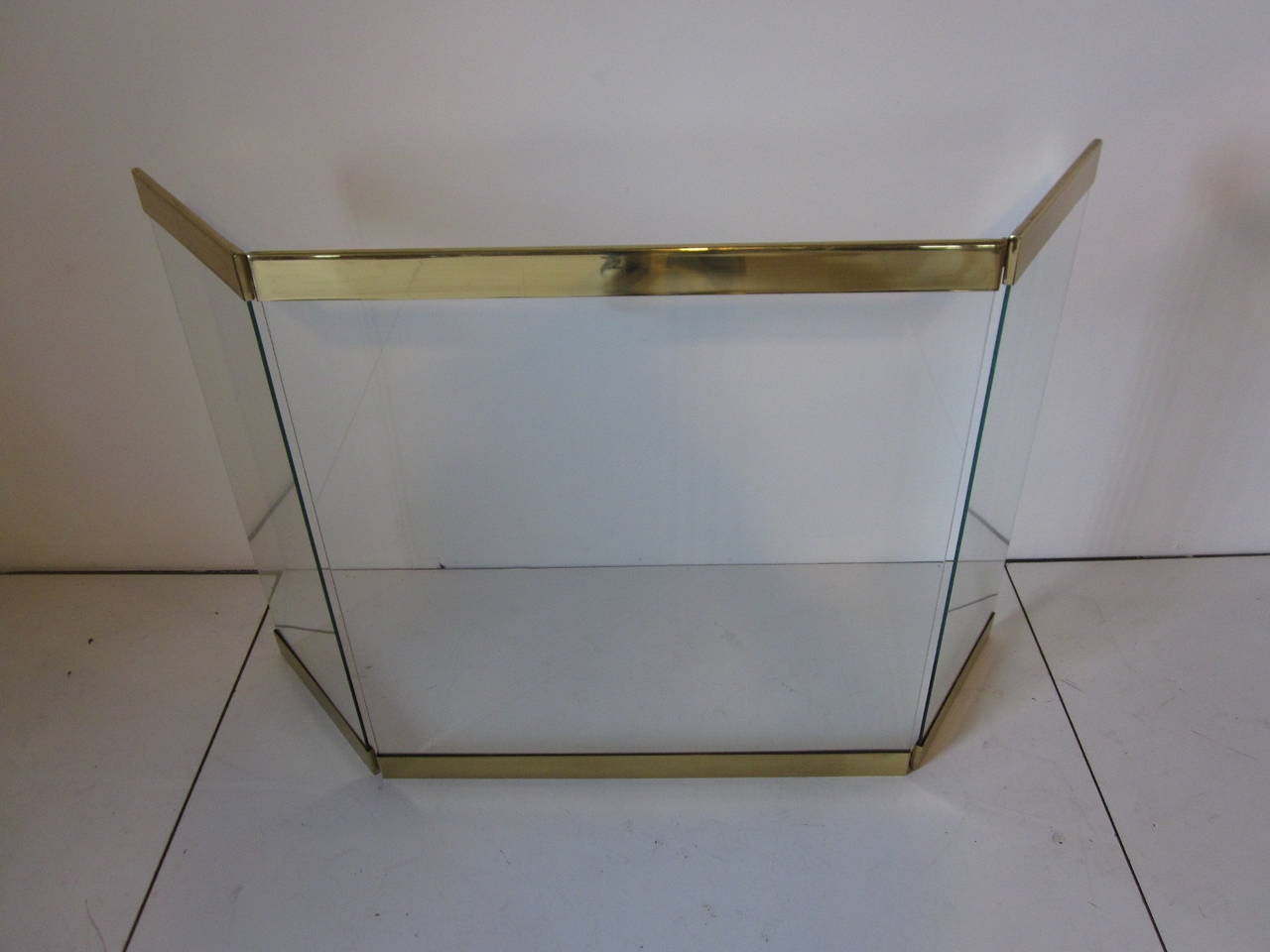 A three-panel plate-glass fireplace screen with heavy brass trim and hinges in the style of designer Leon Pace and Company with a clean modern line. The center panel is 28" and the side panels are 12" wide on each side. Retains the paper