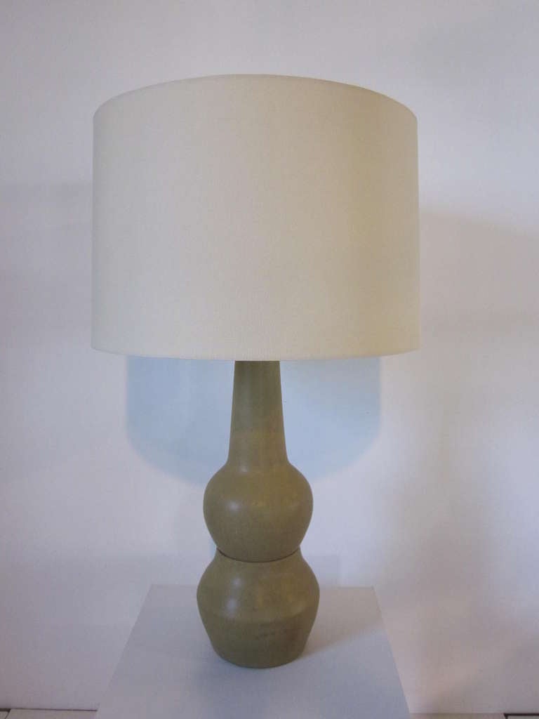 A Mid Century modern Martz studio table lamp in a soft satin dark sand tone with artist signature to the bottom back side and topped with a light sand linen shade dia. measurement is 19