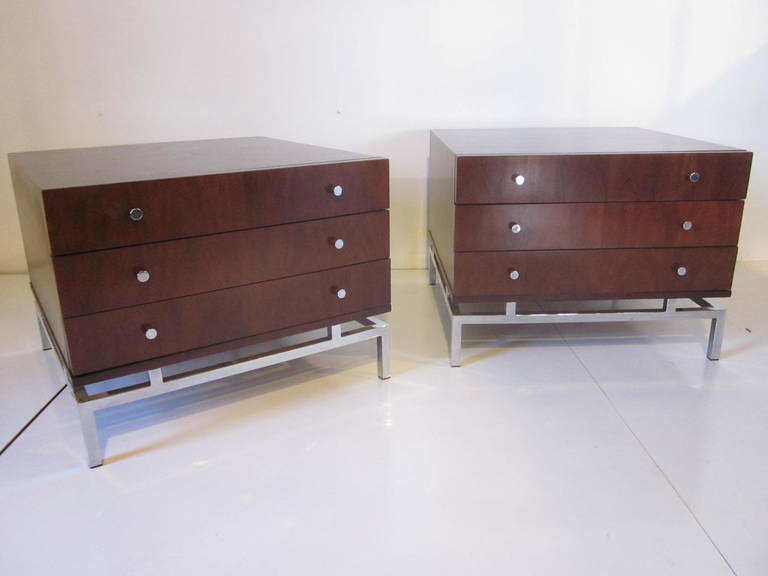 Pair of three drawer nightstands or end tables in dark and rich walnut with chrome pulls sitting on stainless steel bases. Manufactured by the American of Martinsville company.