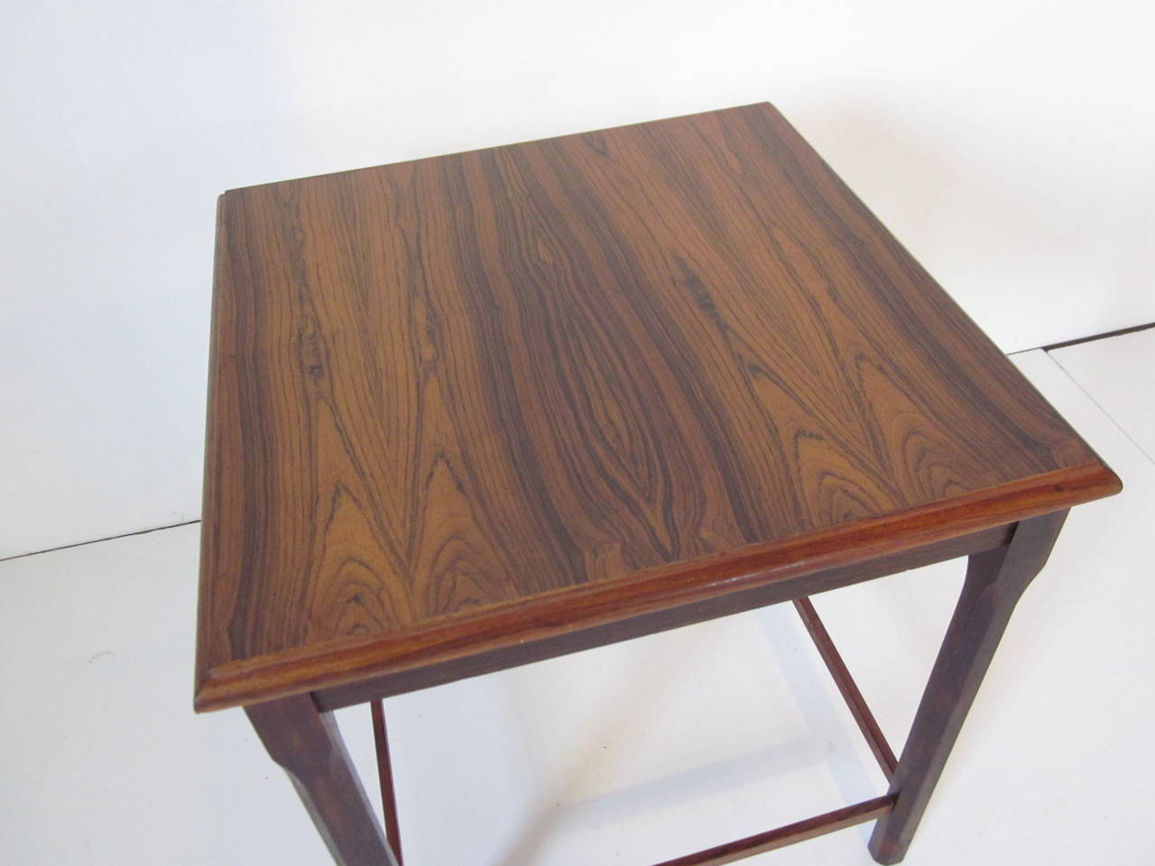 A dark Brazilian Danish rosewood side table with beveled edge construction and lower stretches marked made in Denmark.