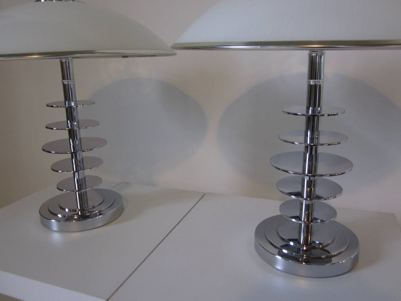 A pair of chrome ringed table lamps with domed glass shades with slight gray toned pinstripes imbedded in the shade with chrome trim and upper CAP with final. In the style of Italian artist Ingo Maurer. Shade size is 18.13