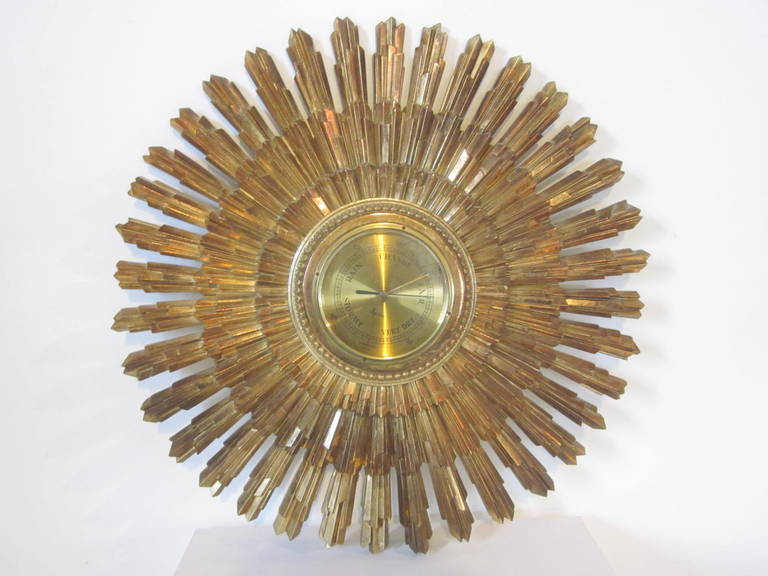 A gilt gold wall-mounted starburst with a brass and glass barometer works made in Germany used as the center piece, marked: Rain, Change, Fair, Very Dry and Stormy designed and manufactured by Syroco.