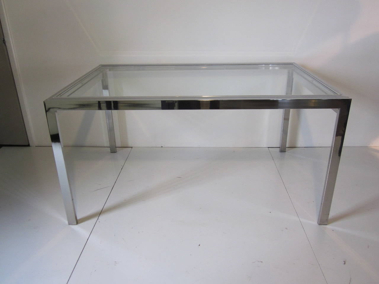 A chrome and glass extension dining table with unique sliding glass two panel leaf system which extends the table to a total of 120