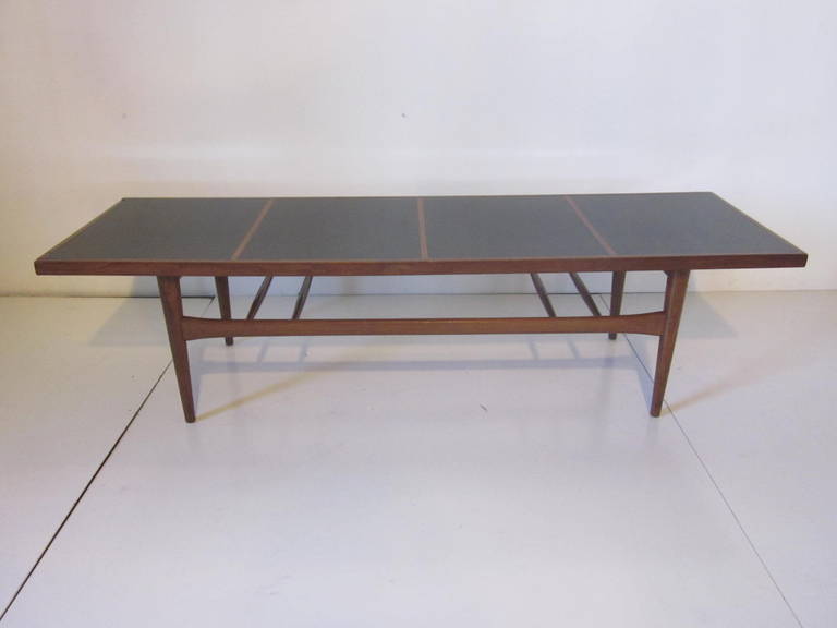 A teak wood framed coffee table with four black laminate inserts to the top surface in the style of Arne Vodder.
