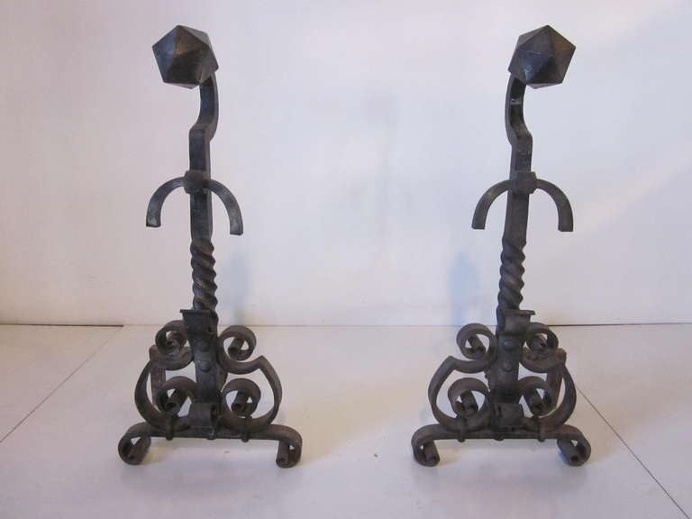 A fantastic monumental pair of finely crafted handcrafted andirons with a set of four matching tools. The andirons have scrolled feet,curled bodies and twisted shafts topped off by large faceted balls.The fireplace tools at 30