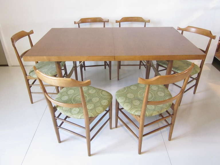 A very rare and early Milo Baughman designed dining table with six chairs.The table has details that normally would not be seen on a set of this period.Curved brass stretchers and brass supports with shapely conical legs and lightly sculptural