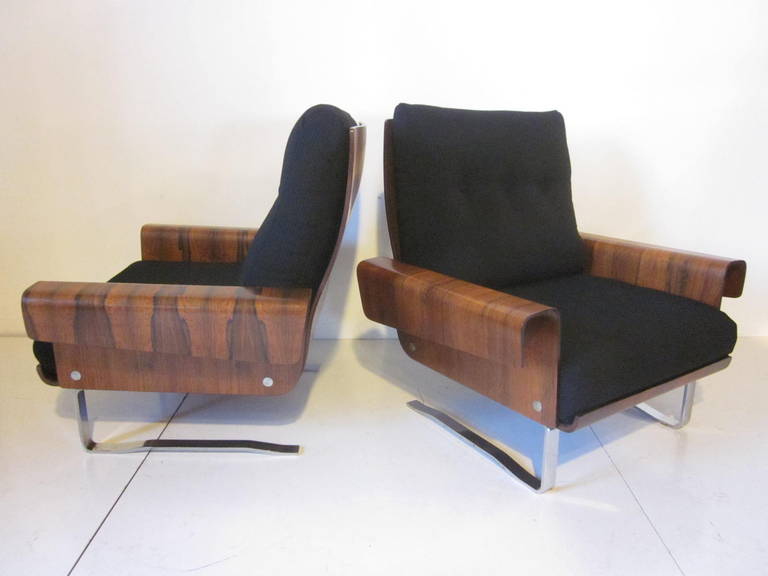 A matching pair of dark rich Brazilian rosewood lounge chairs with cantilevered  chrome bases for spring like support. Two loose upholstered cushions to each chair make for a relaxing supportive lounger, made by the Selig furniture company.