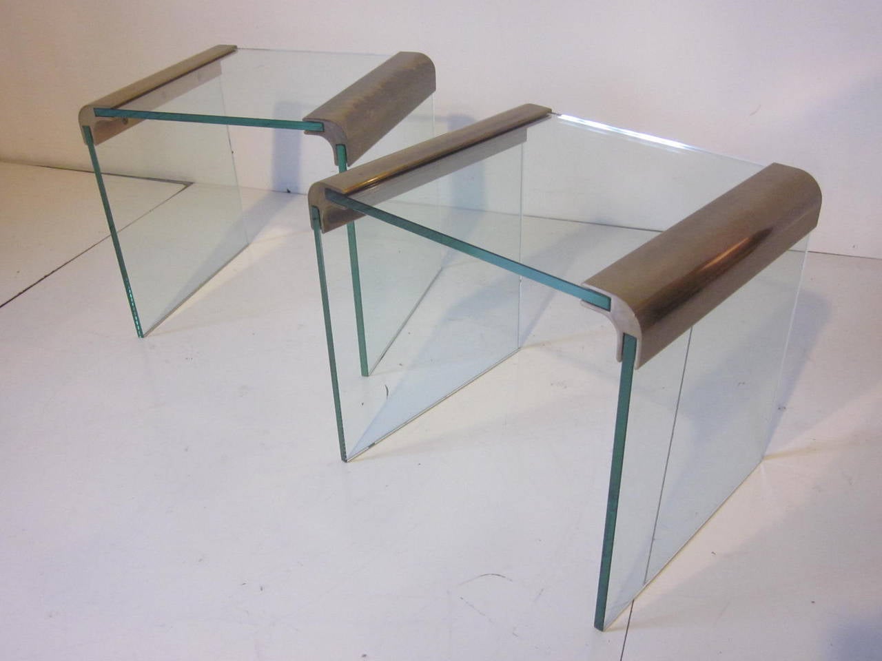 A pair of side tables with stain brushed brass and plate glass tops and legs, from the Pace Collection.
