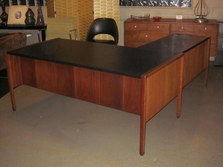 A dark walnut Risom Executive desk with matching return, black leather tops, pencil ,file and three additional drawers. In the right top drawer there's a glass insert and lower storage shelves in the return and desk .Retains the original keys and