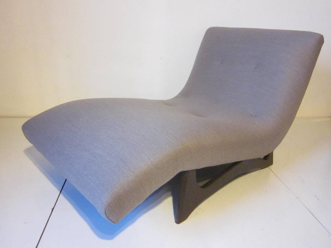 An upholstered wave lounge chair sitting on dark walnut legs manufactured by Craft Associates.