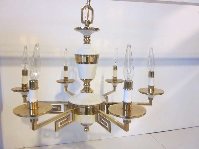 A quality and well constructed brass and off white porcelain chandelier with elegant Greek key and brass detail design.