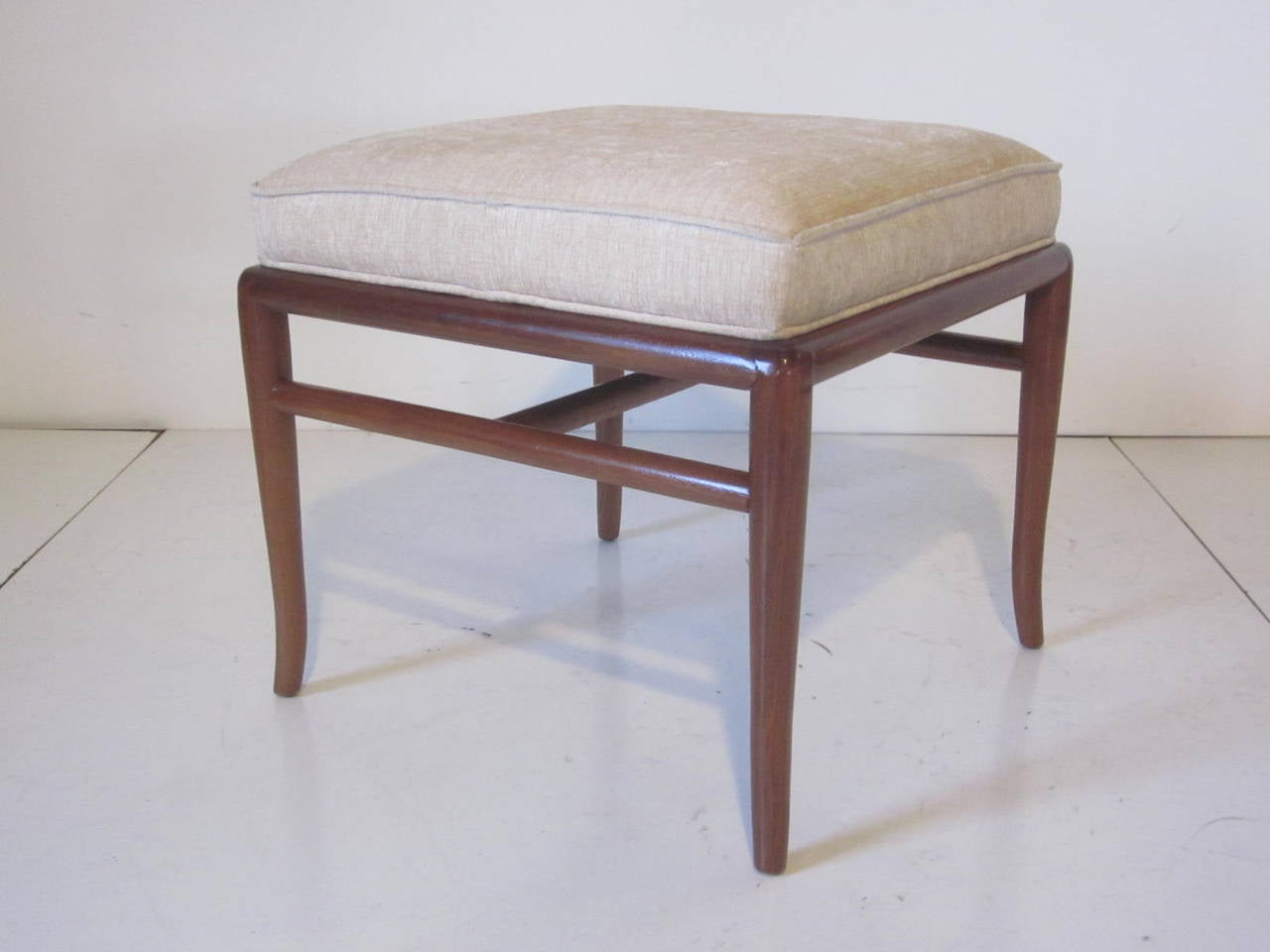 Upholstered stool with medium dark mahogany sabre wood legs and stretchers manufactured by the Widdicomb Furniture Company.