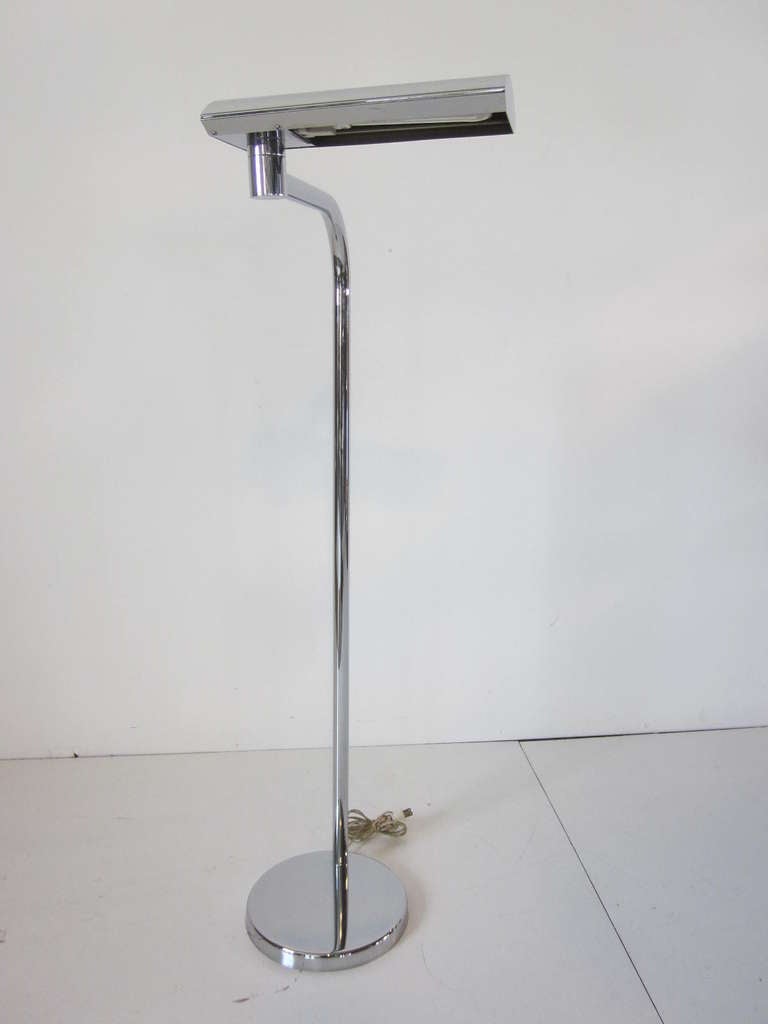A Modern chrome floor lamp with swiveling head which uses a energy conserving long double bulb sitting on a matching base.