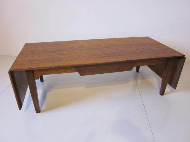A very early Milo Baughman extending coffee table designed for the Drexel Furniture Co. for their Perspective line.Finished in a tiger mahogany,two way center drawer with fold up and locking extended ends.