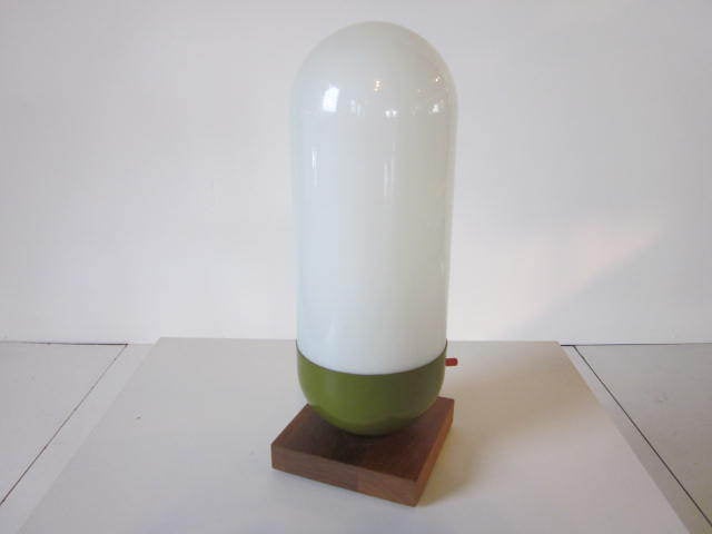 A handblown opal cased glass shaded pill form table lamp with metal lower,walnut base and orange three way switch.Model L-8 made by Design Line and retaining makers tag.