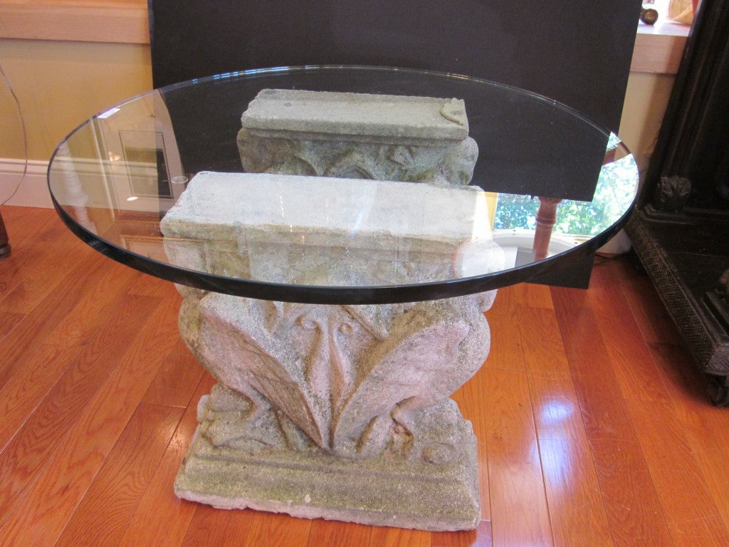 Unique glass top coffee table has antique cement pedestals as base.  Pedestals have interesting bird motif and came out of a Manhattan brownstone.