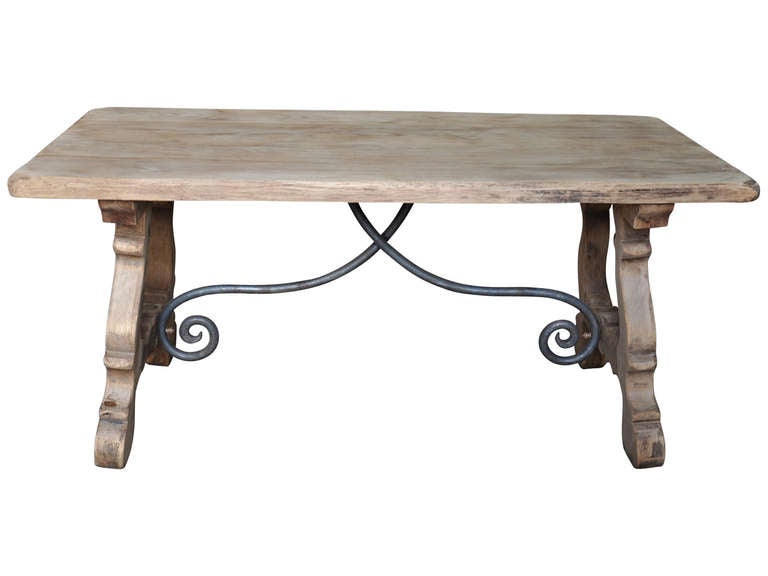 Spanish trestle table from the Catalan region in washed oak and iron. This beautiful table has a lovely iron stretcher detail and lovely carved legs. Use it as a kitchen or dining table, a desk, or even a sofa table. The style and washed oak finish
