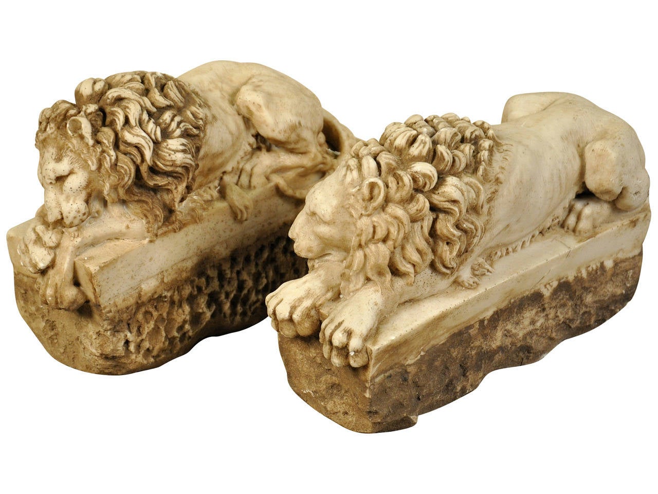 A stunning pair of diminutive hand carved marble lions from Italy.  The resting lions are carved on rectangular plinths atop a rough chiseled base. Both with unique positions of repose.  These lions were originally part of a larger structure.  These