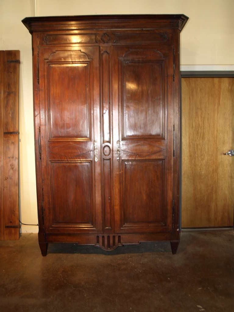 Mid 19th century French antique Louis XVI style armoire in walnut. This gorgeous armoire has clean lines and a warm patina that will suit most styles of decor from traditional to contemporary. This piece has adjustable shelves and two drawers making