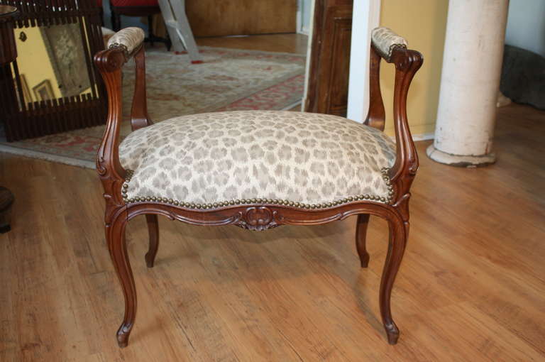French antique Louis XV style footstool in walnut, circa mid 1850's. This beautiful little banquette has recently been reupholstered in a high-quality leopard print linen with a lovely muted gray palette. The patina is warm and inviting and the