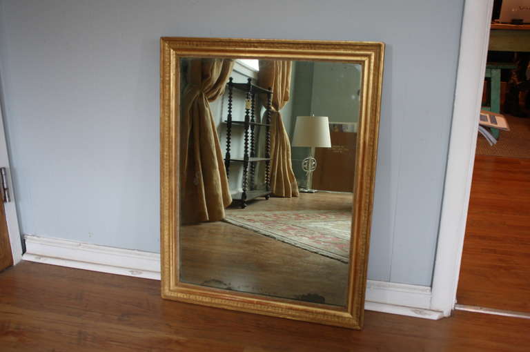 French antique Empire period mirror from the early 19th century in gilt wood. This lovely mirror has the original patina & mercury glass. The lines are clean and make it perfect for use in just about any room in your home including a powder room or