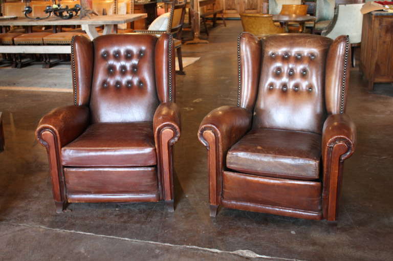 Pair of French Art Deco leather club chairs from the 1930s. These chairs have beautiful curved lines, nail head trim, and a beautiful patina. They are perfect for use as office chairs, or chairs for a library, living room, or study.