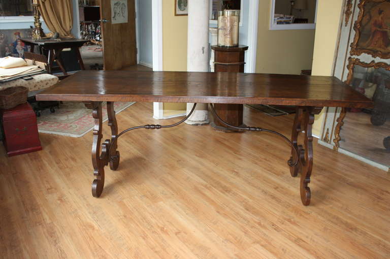 A very handsome 19th century Spanish Baroque style Farm Table/ Trestle Table with hand forged iron stretchers from the Catalan region.  This very elegant table is constructed from Walnut and serves as a wonderful dining table, breakfast table, sofa