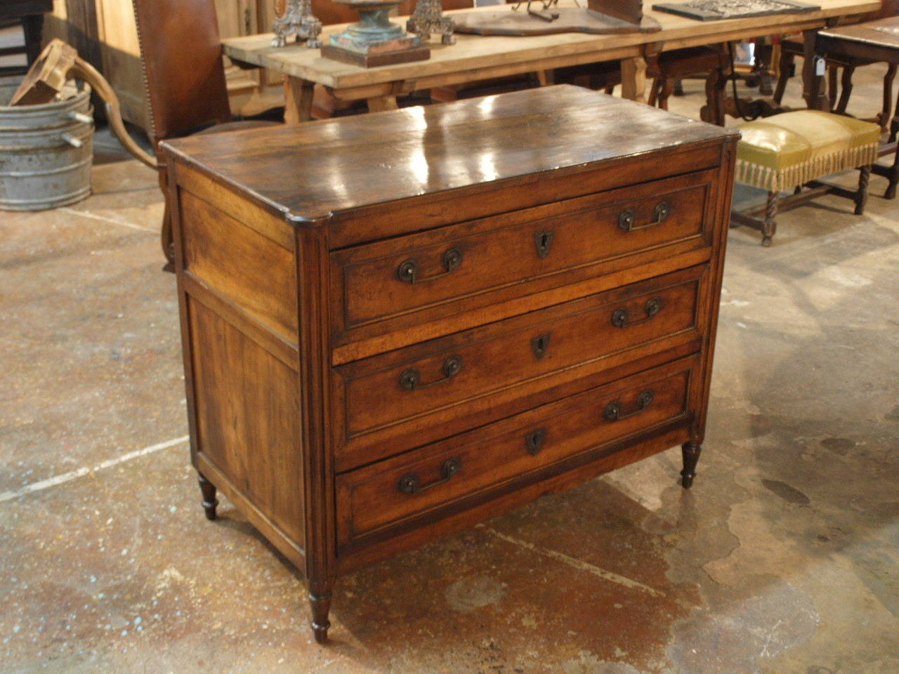 A stately and handsome French 18th century period Louis XVI commode in walnut. Beautifully constructed with a rectangular top with rounded front corners above a conforming case with fluted columnar supports housing three drawers with original brass