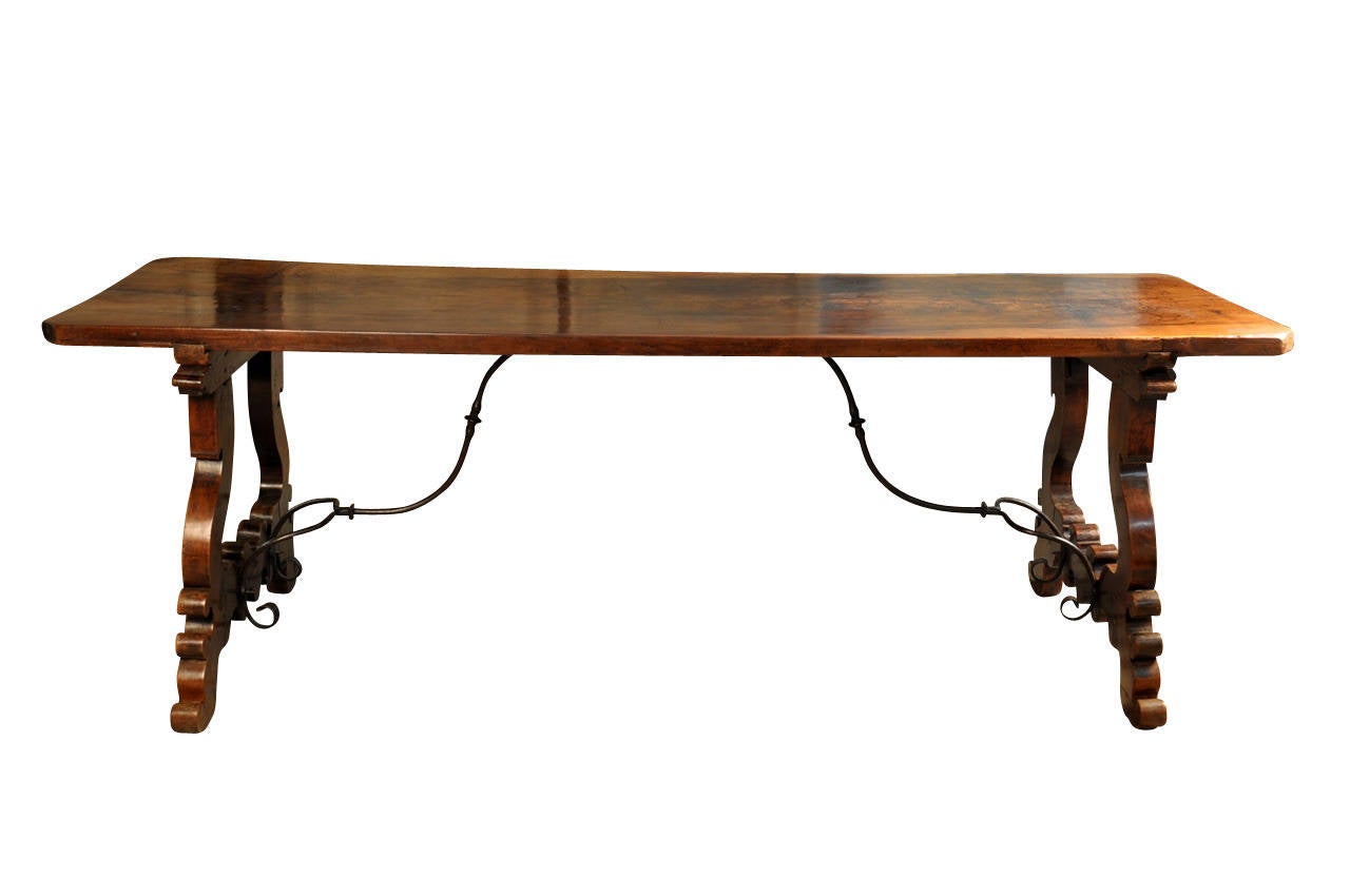 A stunning 18th century Spanish farm table - trestle table constructed from walnut with a solid board top and hand wrought iron trestles.  This is an exquisite table.  The solid board top is indeed impressive and has a very rich and luminous patina