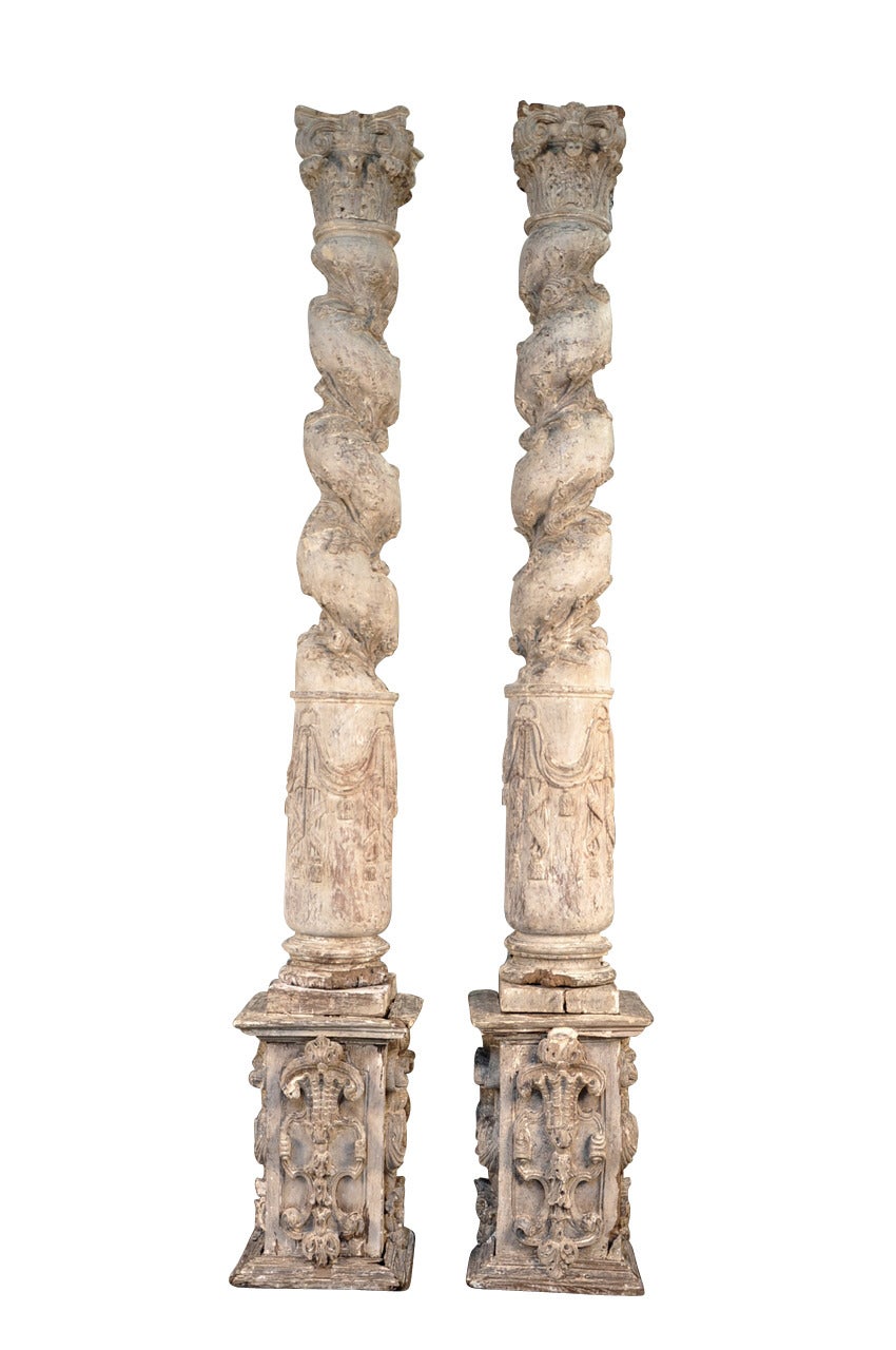 Monumental pair of 17th century Solomonic columns and their pedestals from Portugal. Beautifully carved spiraling shafts adorned with flowering vines and crowned with Corinthian capitals. A stunning accent.