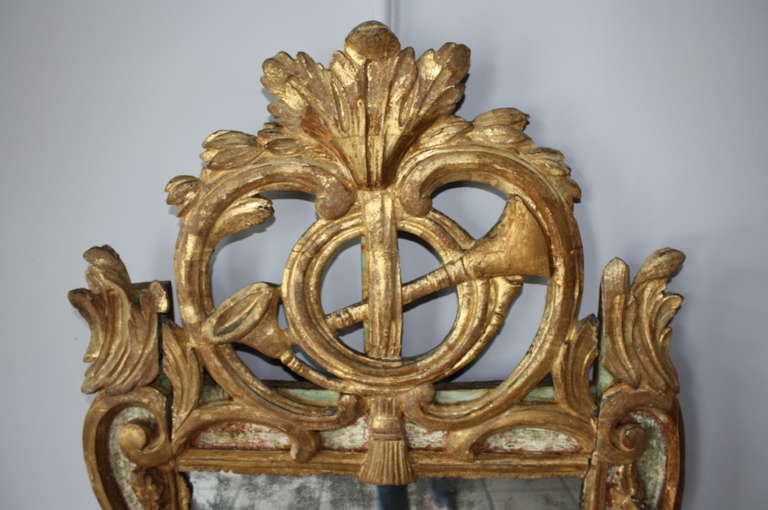 A stunning Louis XV period Parcloses Mirror from France.  Polychromed in part in burnt sienna and green, then water gilded.  Beautifully carved with a musical motif, oak leaves and acorns.