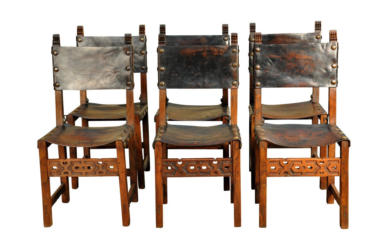 A very handsome set of six Spanish dining chairs - side chairs - in richly stained oak and leather with wonderful large nail heads.  The leather is in wonderful condition and has a very deep patina.