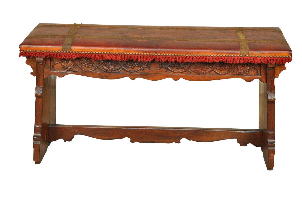 A charming mid 19th century Spanish bench constructed from walnut and leather.  Beautifully carved with a grape and vine motif on the apron and a draping motif on the legs.