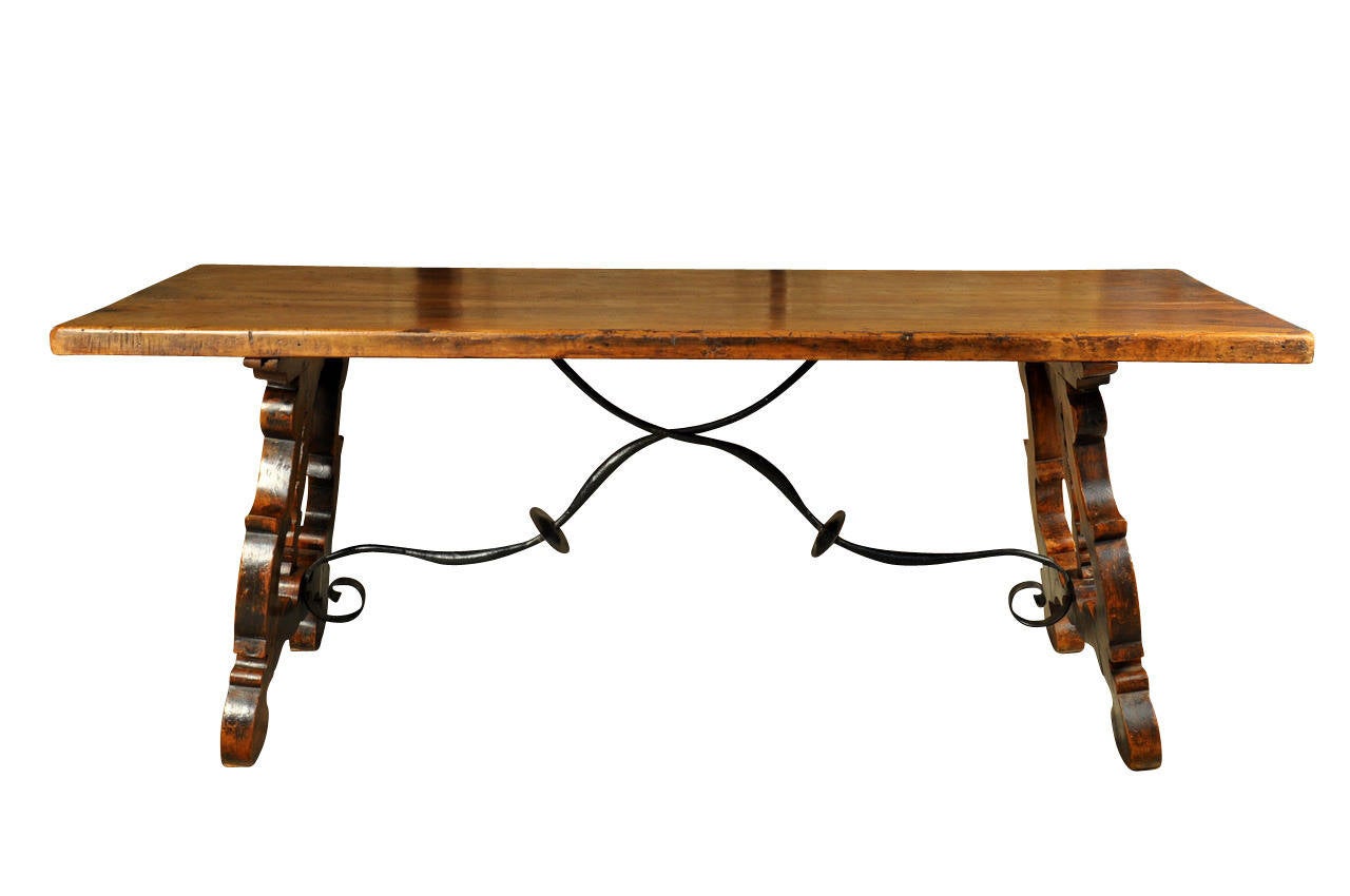 A very handsome Spanish 19th century farm table - trestle table in walnut and hand forged iron stretchers.  This table is constructed from thick planks and is very sturdy and sound.  The patina is rich and luminous.  Wonderful not only as a dining
