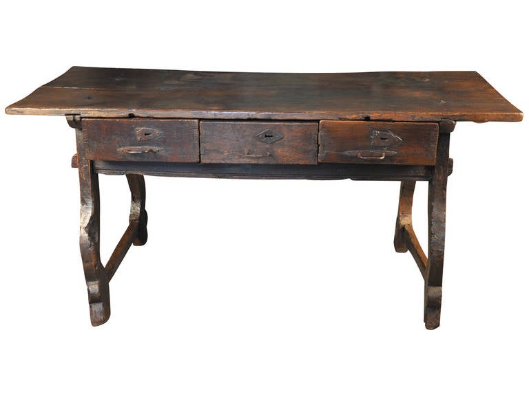 A tremendous 17th century primitive table constructed from walnut and chestnut woods from the Catalan region of Spain. The top of this outstanding table is made from a solid board. The patina is so rich and luminous with beautiful grain patterns.