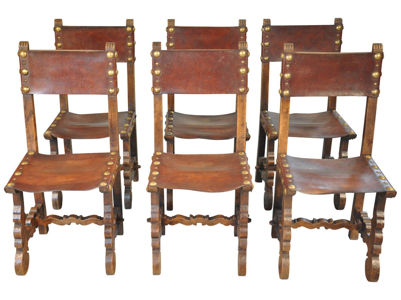 A set of 6 Spanish leather dining chairs in the Baroque style.  Beautifully constructed from walnut with handsome nail head detail.  The leather has a very sumptuous patination.