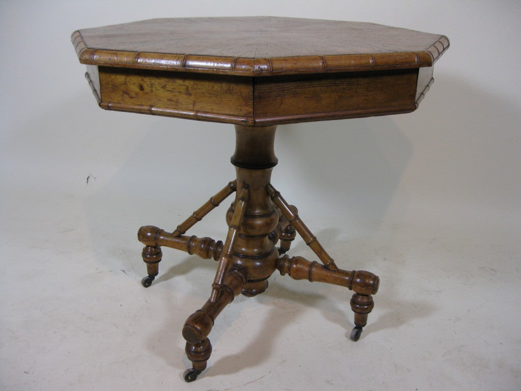 This octagonal center table is characterized by a bamboo motif detail throughout and a beautifully turned pedestal base. The top contains two opposing drawers. The top is made of quarter sawn pine which radiates from the center.