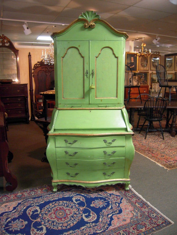 A quality Italian secretary in the Maison Jansen style.  Circa 1940, this decorative piece features a shell carving atop an arched crest.  Two doors, a drop front desk, and four Bombay drawers are supported by cabriole feet.  A vibrant citrus green