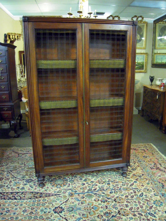 Mahogany bookcase with wire doors, velvet and brass edge trim. Excellently sturdy, understated, and beautiful.