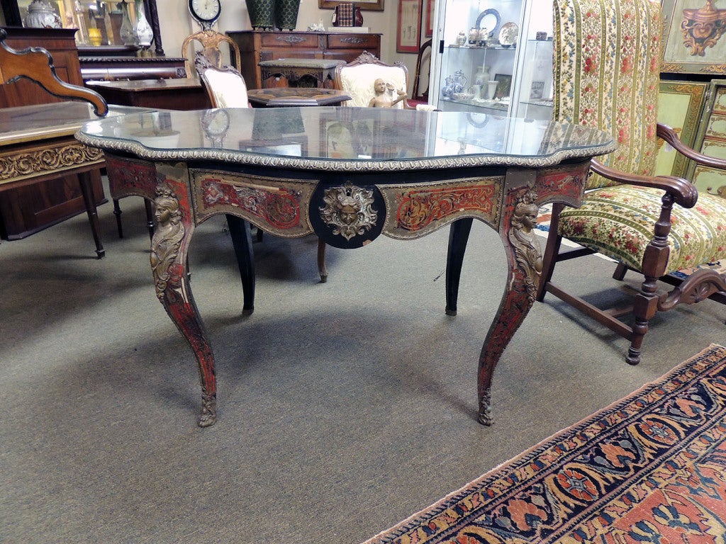 Ornate brass and tortoise inlaid center table, in the style of Andre’ Boulle. Spectacular ormalu mounts enhance this grand table, with center drawer. Minor repair is suggested, as pictured.