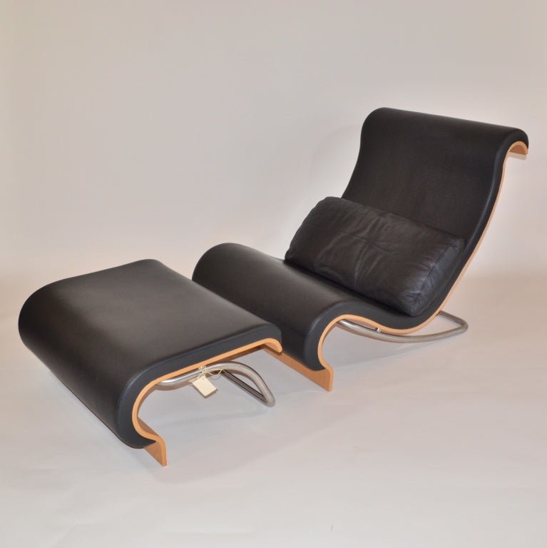 Designed in 1965 by Jørn Utzon, the architect behind the Sydney Opera House, this easy chair and footstool is upholstered in black leather and includes a loose back cushion. This beautiful chair was originally designed for the Opera House but never