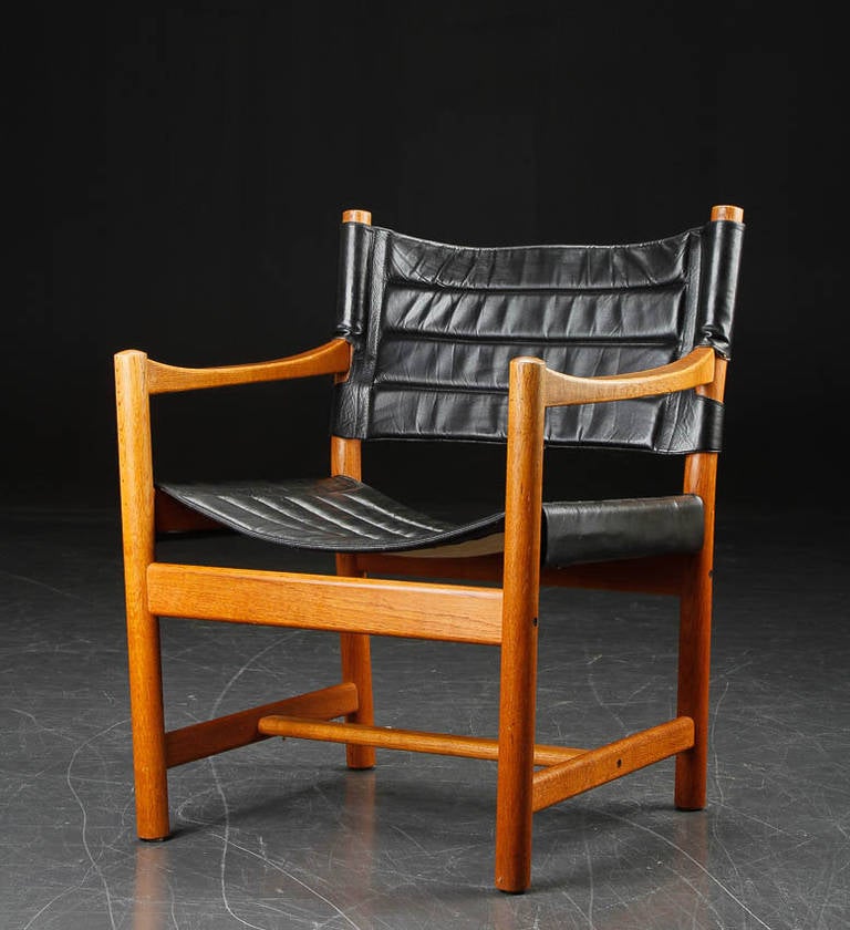 Classic armchair by Danish designers Adrian and Ditte Heath. Made of solid oakwood with black leather strap in back of chair. Seat and back also of black leather. Produced by FDB (Denmark).