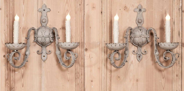 Pair Country French Hand Forged Wrought Iron Painted Sconces featuring fine detail and fleur de lys motifs.  Rewired to US standards by our expert in-house staff.  Originally painted in soft grey tones with antique patina. Circa early 1900's. 
Each