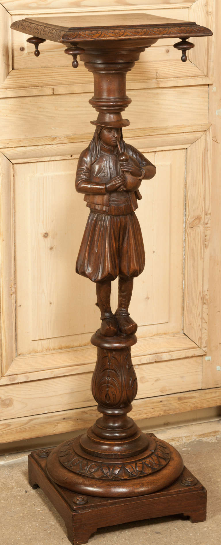 Always a favorite, the whimsical nature of carved wood antiques from Brittany bring smiles to everyone's faces.  This Antique Brittany Pedestal features a finely dressed young bagpipper atop a finely carved pediment and base.  Even the top surface