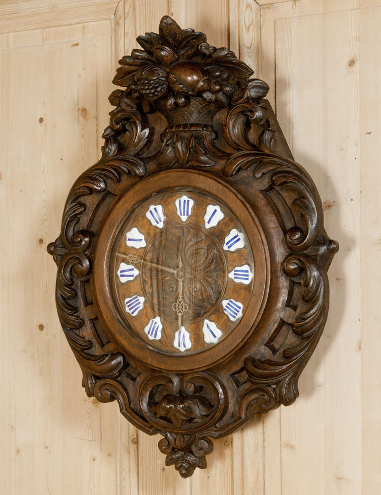 Boasting a casework comprised entirely of hand-sculpted white oak that depicts classical bounty-of-the-Earth themes, this Antique Renaissance Wall Clock survives with its original hand-painted porcelain numerals and filigreed hands, surrounding a