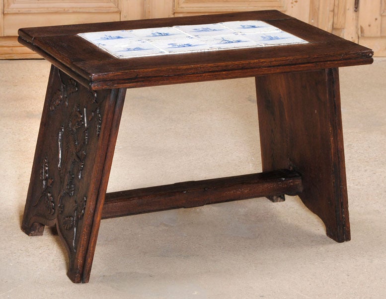 Hand-crafted from solid European white oak by the master artisans of Delft, then carved with an exquisite stylized lion motif on each side support, then finally finished with 18th century hand-painted Delft tiles on top, this antique table adds