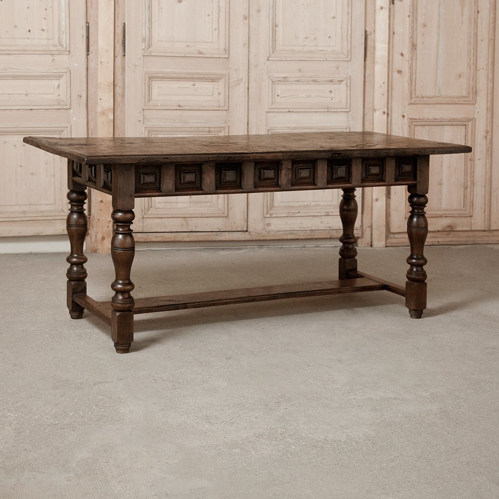 This antique rustic Italian 18th century desk features a weathered top and a pair of finely carved drawers fitted with forged iron pulls. Sturdy turned legs are connected with the Classic 