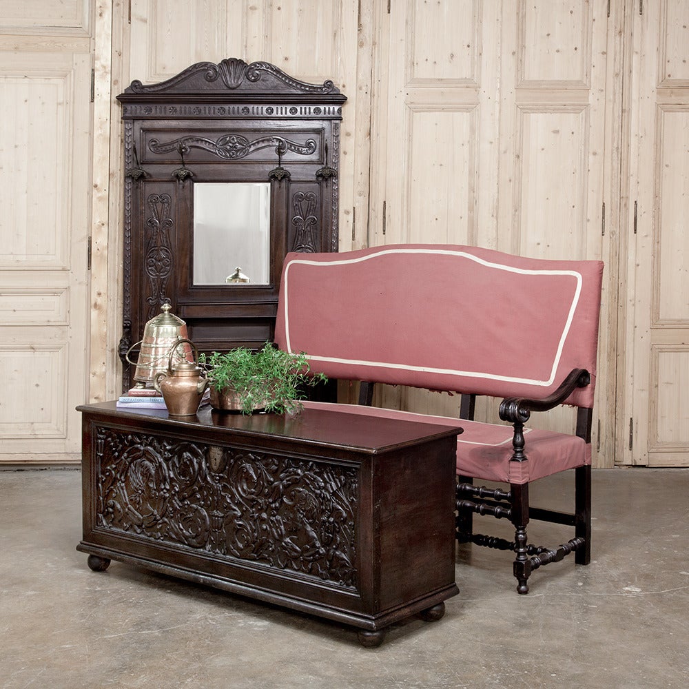 Bench-made antique furniture crafted in Italy in fine walnut and is an ideal foyer companion, this antique Italian Renaissance hall tree was surround by exquisitely carved panels on each side of the full length beveled central mirror, then fitted